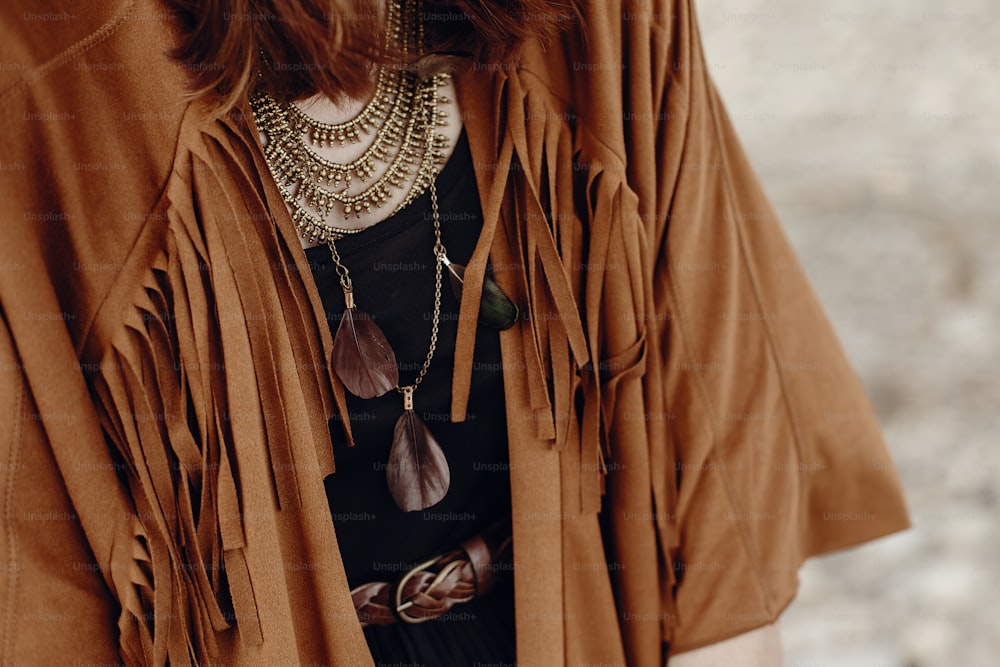 stylish boho woman look. gypsy hipster girl in fringe jacket with feather bronze accessory. wanderlust summer travel. atmospheric moment. space for text.