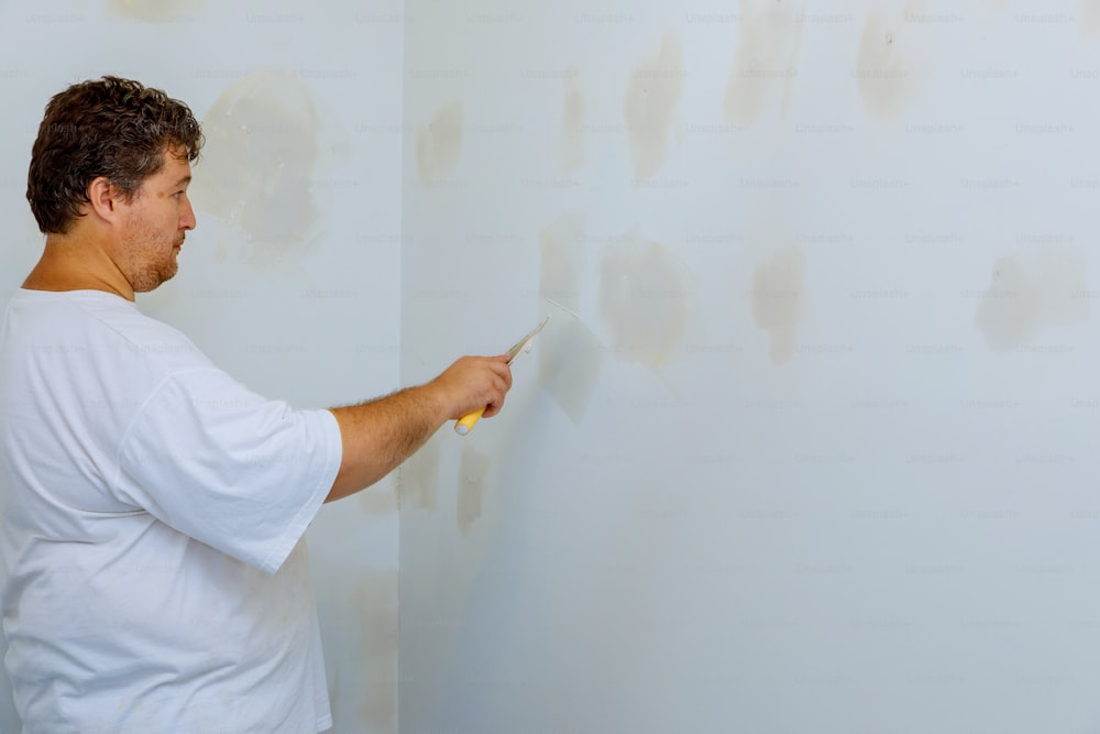 Améliorations de la maison. mettre du plâtre sur le mur avec une spatule main tenant l’outil de plâtrage