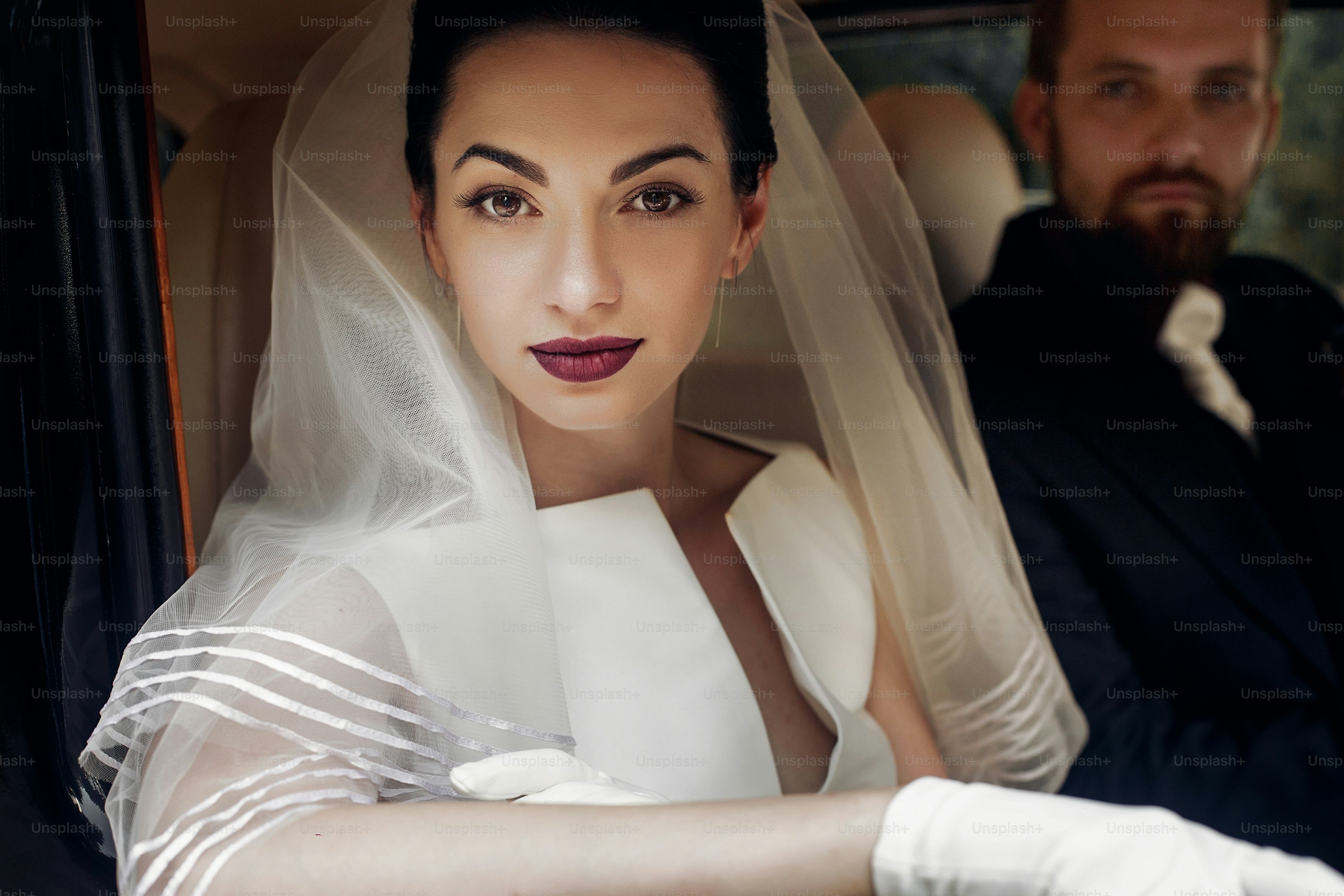 Pareja de novios elegante de lujo posando en un elegante coche negro. Magnífico retrato de novia y novio guapo en estilo retro. Momento romántico