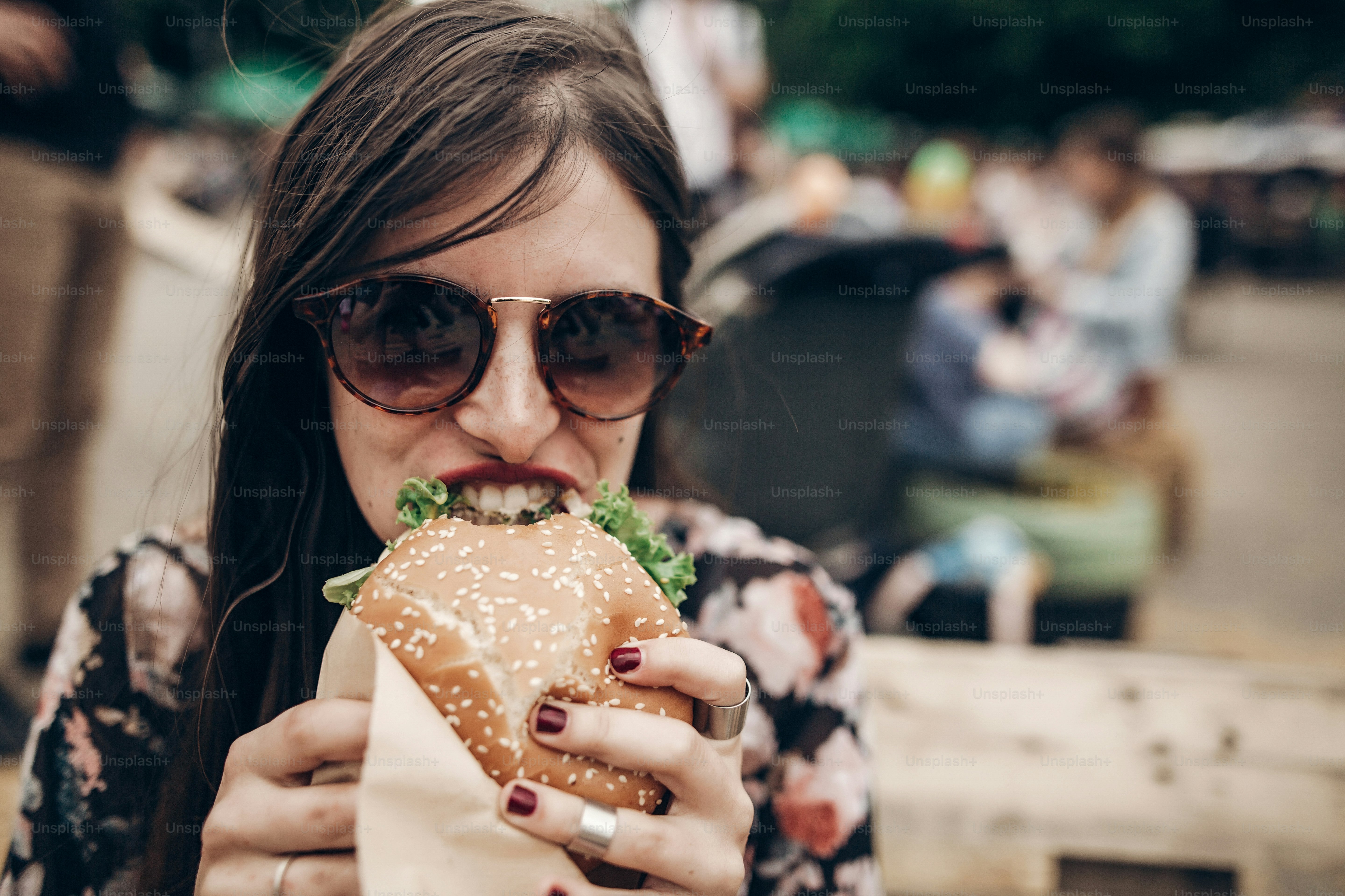 Stylish hipster woman eating juicy burger. boho girl biting yummy ...