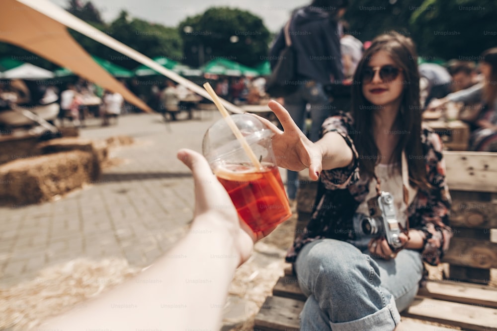 strawberry lemonade in hand. stylish hipster woman in sunglasses with red lips receiving lemonade. cool boho girl with cocktail at street food festival.  summer vacation. space for text