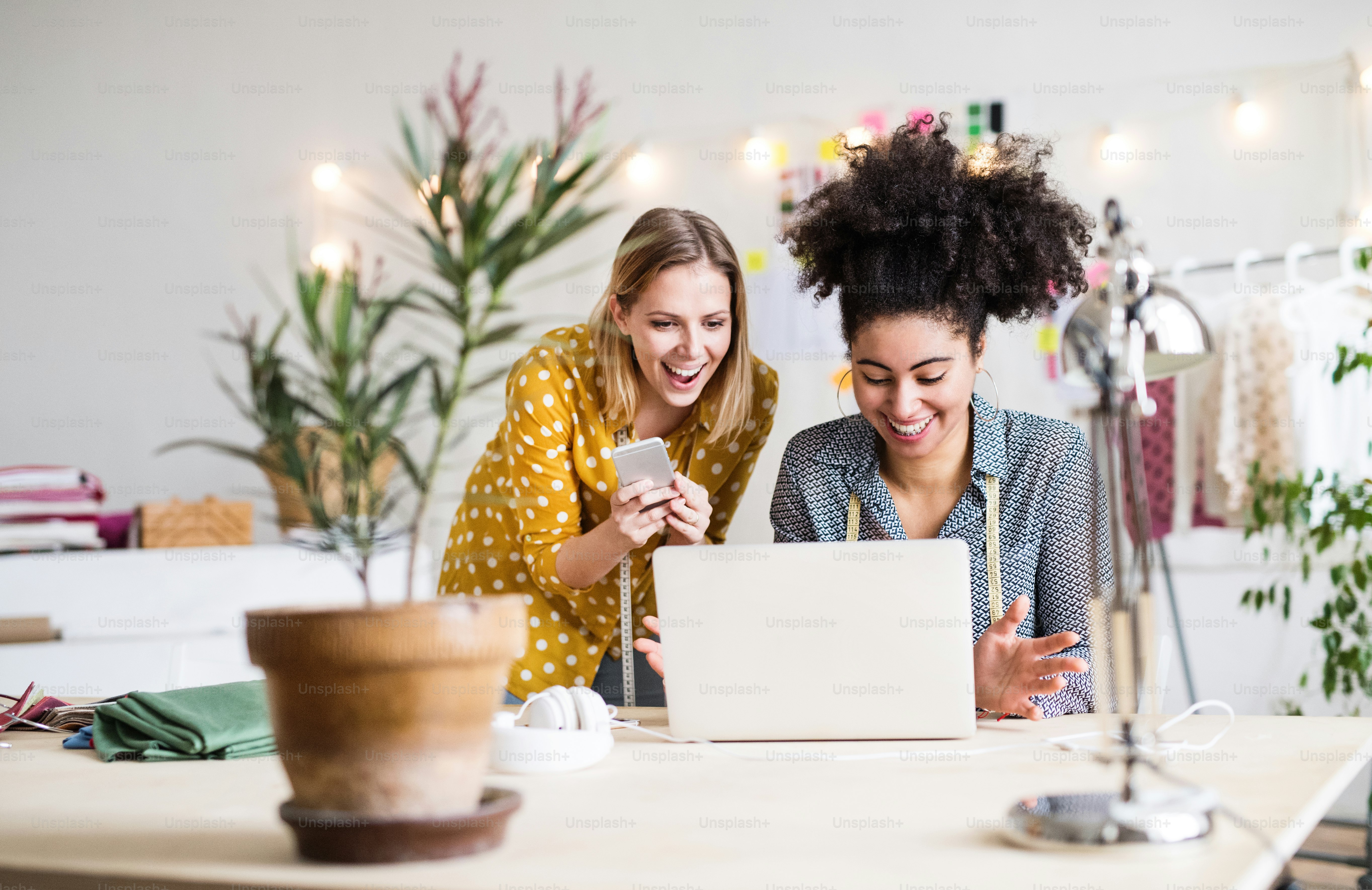 Wanita muda kreatif dengan laptop dan smartphone bekerja di studio, bisnis startup