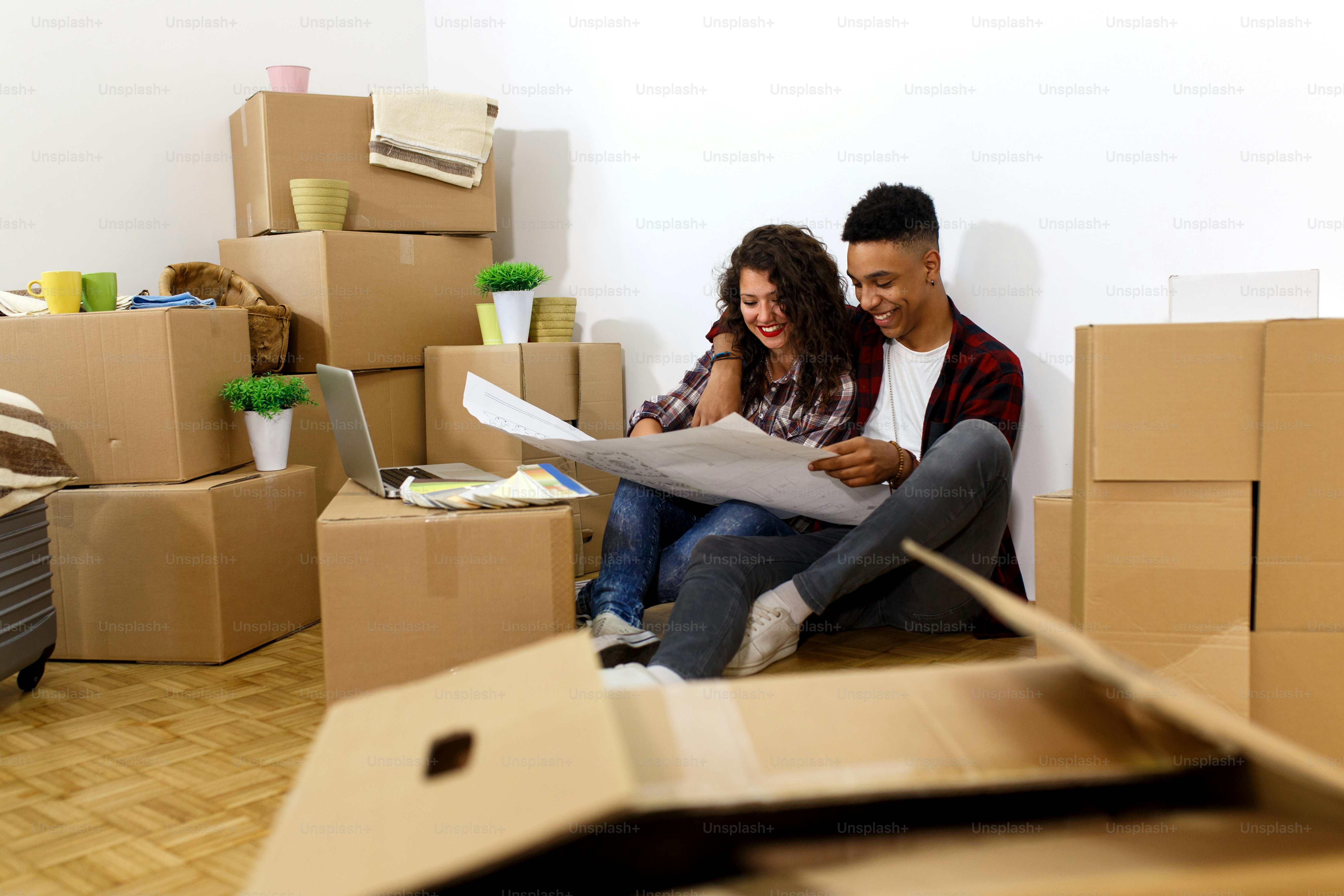 Happy young couple moving into their new home. They sitting on the ...