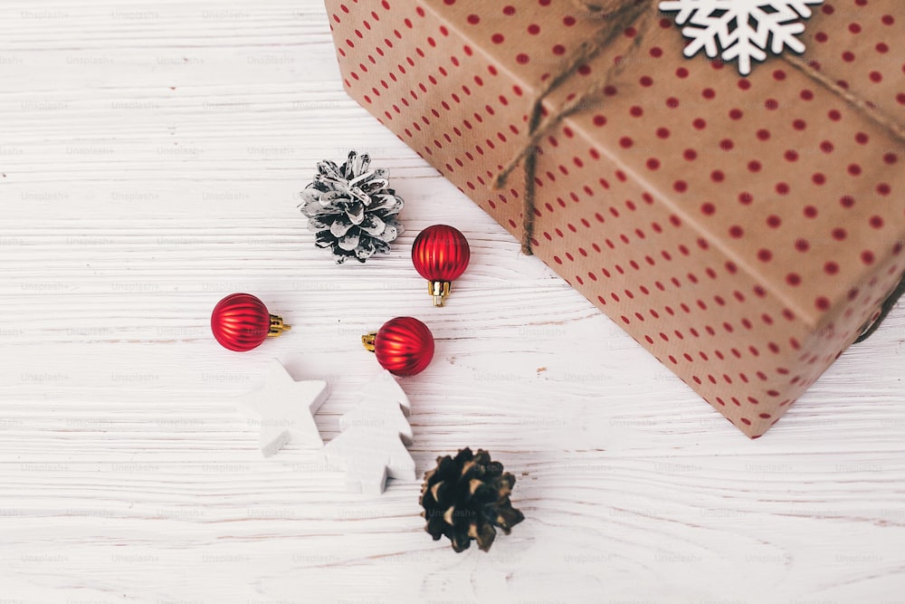 Stilvoll verpackte Geschenkbox Draufsicht, mit roten Ornamenten Baum und Kegel. Handwerk vorhanden. Weihnachtsgrüße, frohe Festtage. Frohe Weihnachten und ein glückliches neues Jahr. Platz für Text