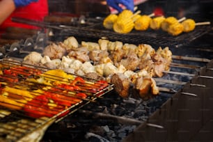 delicious vegetables  and meat grilling on open grill, outdoor kitchen. food festival in city. tasty food peppers zucchini roasting in basket, food-court. summer picnic