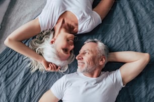 Love lives forever! Top vie of senior couple at home. Handsome old man and attractive old woman are enjoying spending time together while lying in bed.