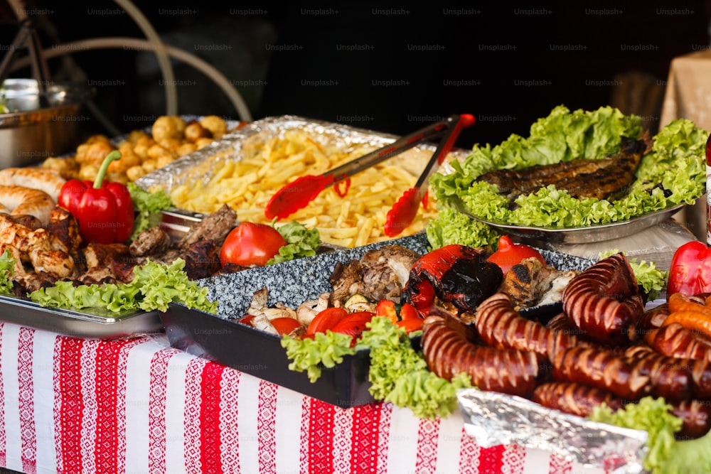 delicious sausages bbq vegetables on open grill, serving at outdoor kitchen. food festival in city. tasty food roasting, food-court. summer picnic