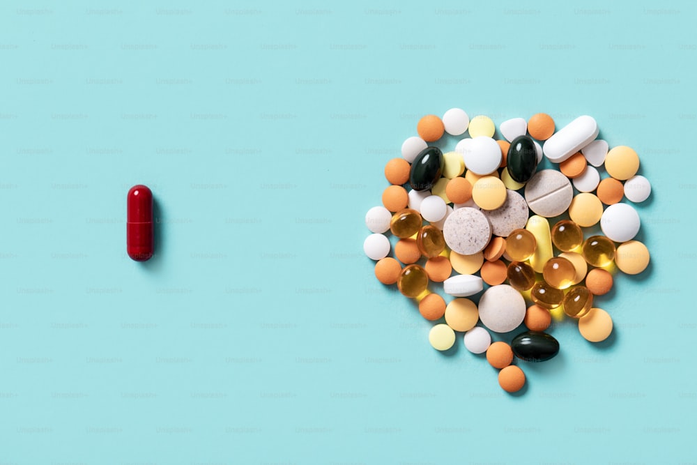 choice between one red pill and different colorful pills on blue background