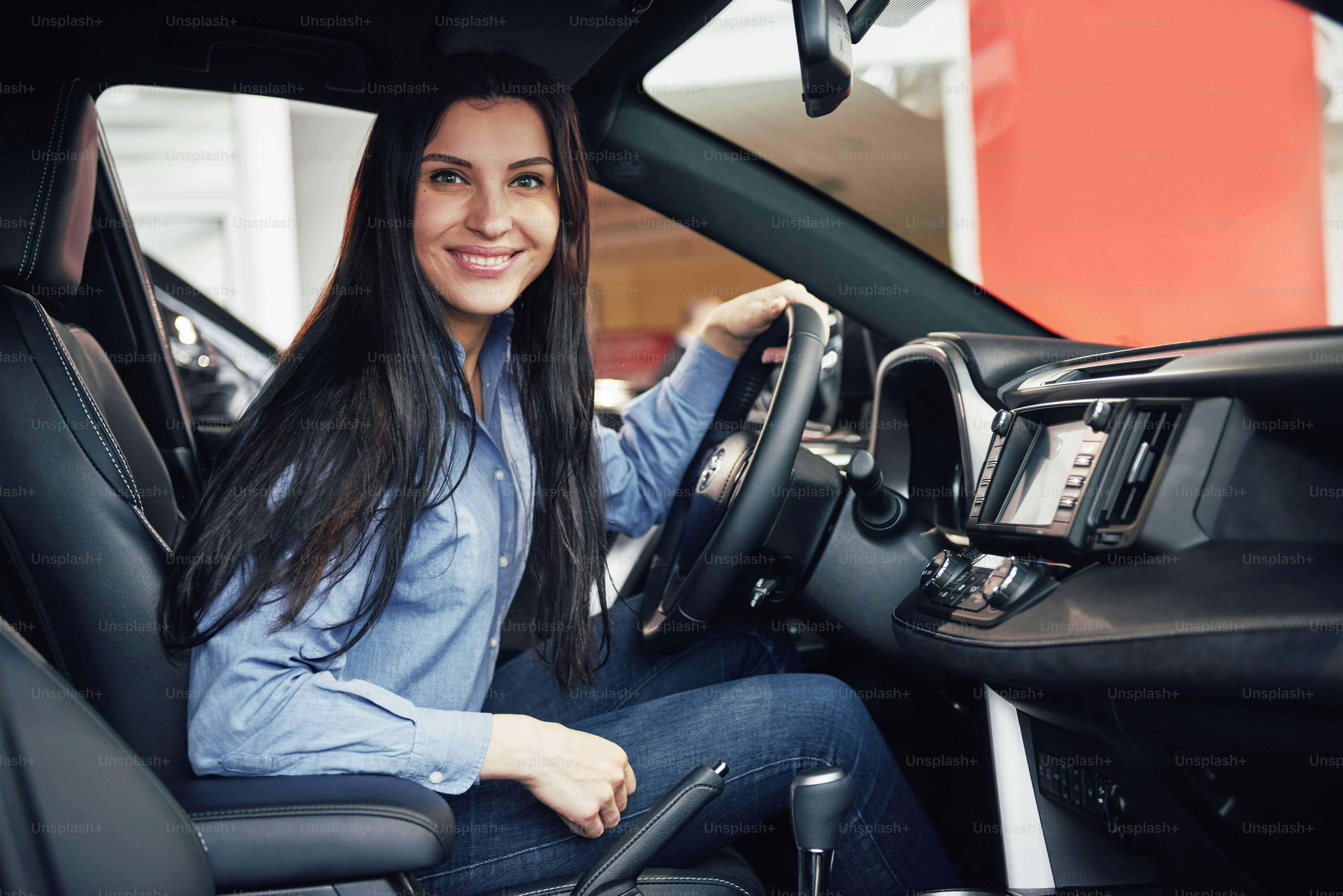 auto business, car sale, consumerism and people concept - happy woman taking car key from dealer in auto show or salon