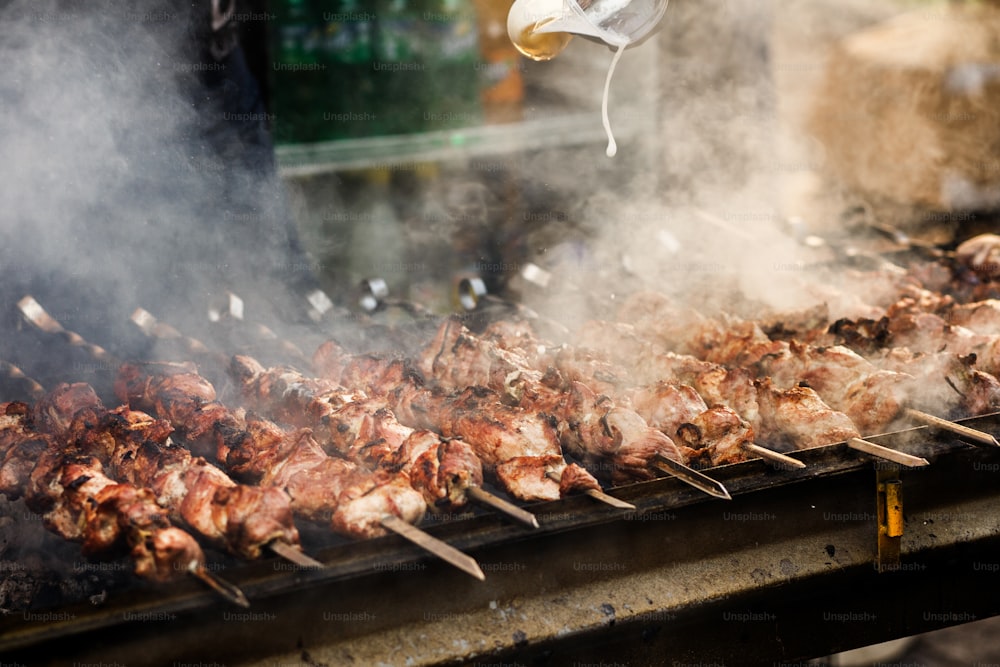 Delicioso kebab de barbacoa a la parrilla en parrilla abierta, cocina al aire libre. Festival gastronómico en la ciudad. Comida sabrosa asada en brochetas, patio de comidas. Picnic de verano