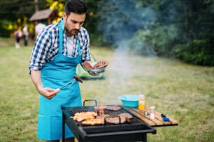 자연에서 야외에서 바베큐 고기를 굽는 행복한 남성