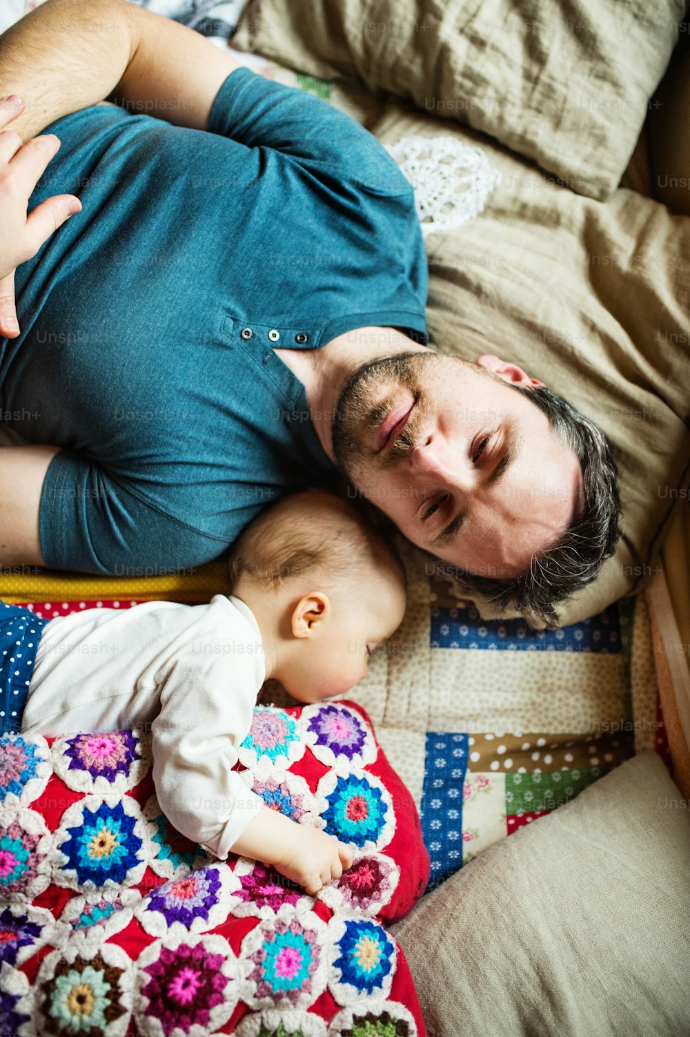 Vater mit einem kleinen Mädchen zu Hause, schlafend auf dem Sofa. Vaterschaftsurlaub. Draufsicht.
