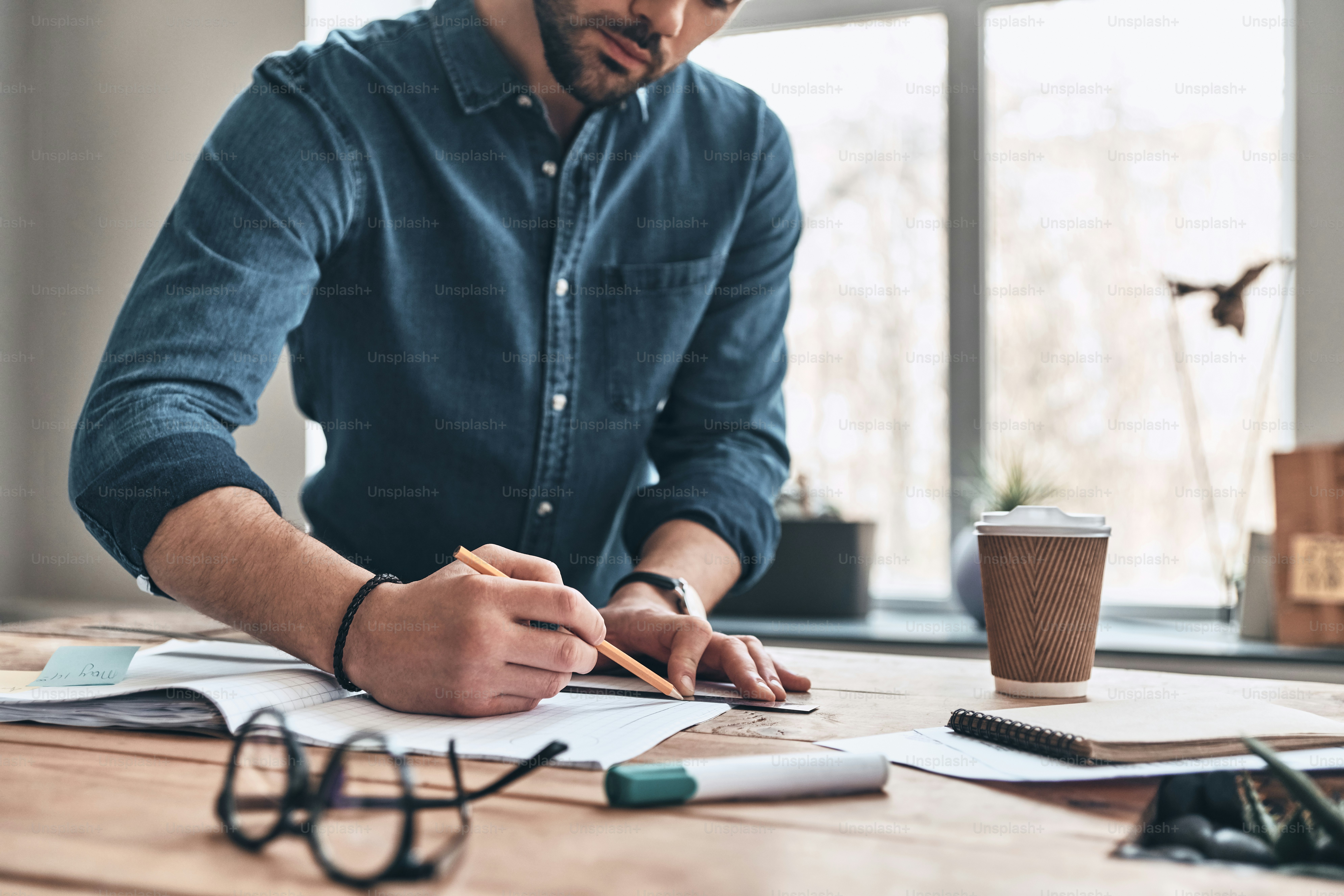 Close up of young man drawing with ruler and pencil while working in the creative working space