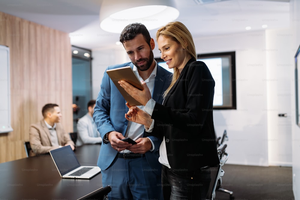 Businesspeople discussing while using digital tablet in office together