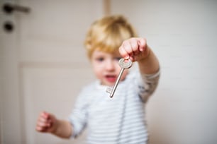 ドアの鍵を持つ小さな幼児の男の子。家庭内事故。自宅での危険な状況。