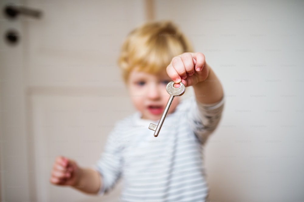 Little toddler boy holding a door key. Domestic accident. Dangerous situation at home.