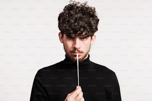 Portrait of a young man in a studio, pulling a chewing gum.