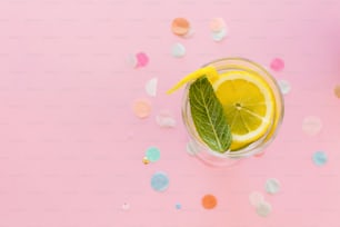 모히토 칵테일 음료는 색종이 플랫 레이가 있는 트렌디한 분홍색 종이 배경에 있습니다. 레몬과 민트로 신선한 음료수. 텍스트 공간. 여름 방학. 휴가 및 파티 개념