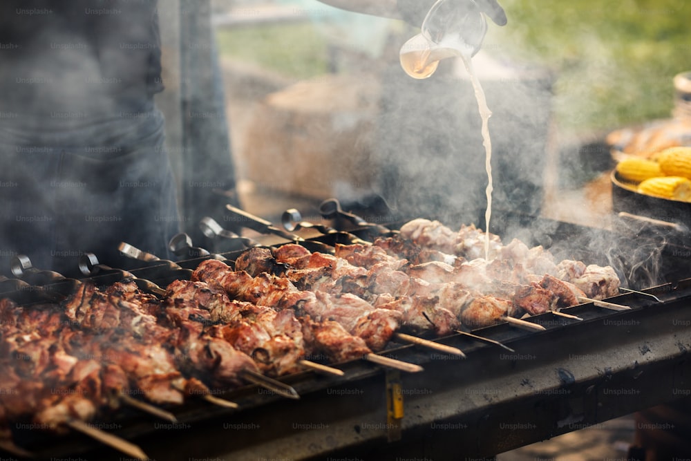 Delizioso barbecue kebab alla griglia su griglia aperta, cucina all'aperto. festival gastronomico in città. gustosa arrostitura su spiedini, food-court. picnic estivo