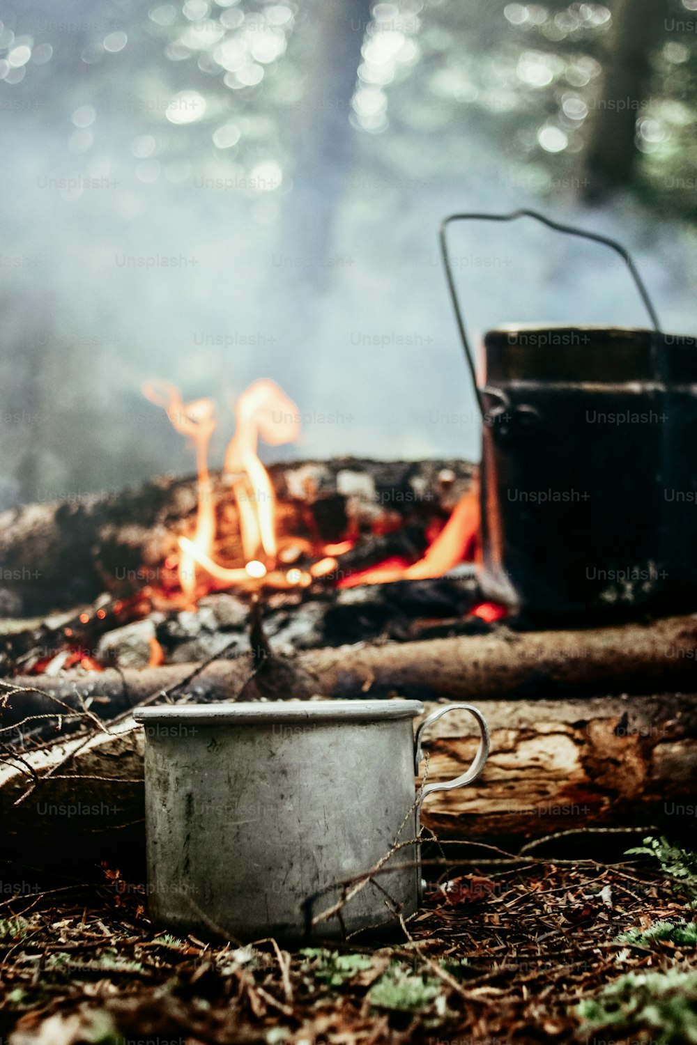 stylish metal cup and kettle in sunny forest in the mountains