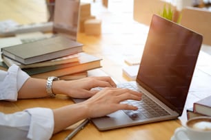 Cropped shot of businesswoman using laptop at her desk at studio office.