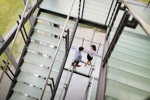 Gente de negocios moderna que camina por las escaleras en la sala de cristal del edificio de oficinas