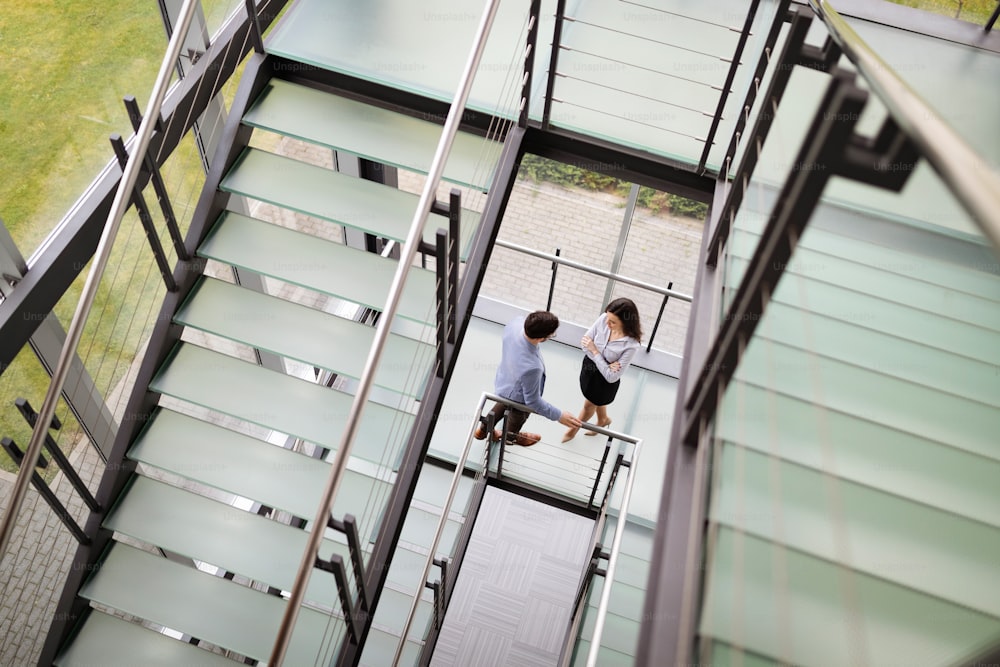オフィスビルのガラスホールの階段を歩く現代のビジネスマン