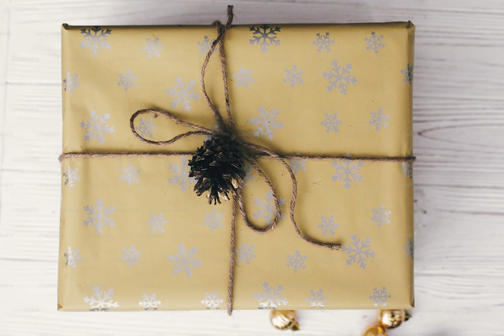 Frohe Weihnachten und ein glückliches neues Jahr. Stilvoll verpackte Geschenkbox Draufsicht, mit Ornamenten und Tannenzapfen. Weihnachtsgrüße, frohe Festtage. Heutige Flachlage