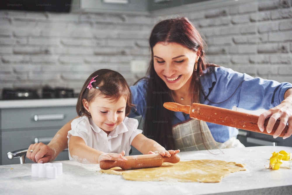Happy family in the kitchen. Holiday food concept. Mother and daughter preparing the dough, bake cookies. Happy family in making cookies at home. Homemade food and little helper.