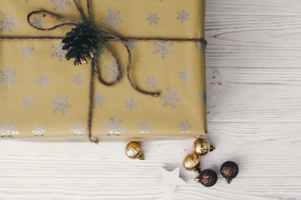 Stilvoll verpackte Geschenkbox mit goldenen Ornamenten. Gegenwärtige flache Liege. Weihnachtsgrüße, frohe Festtage. Frohe Weihnachten und ein glückliches neues Jahr. Platz für Text