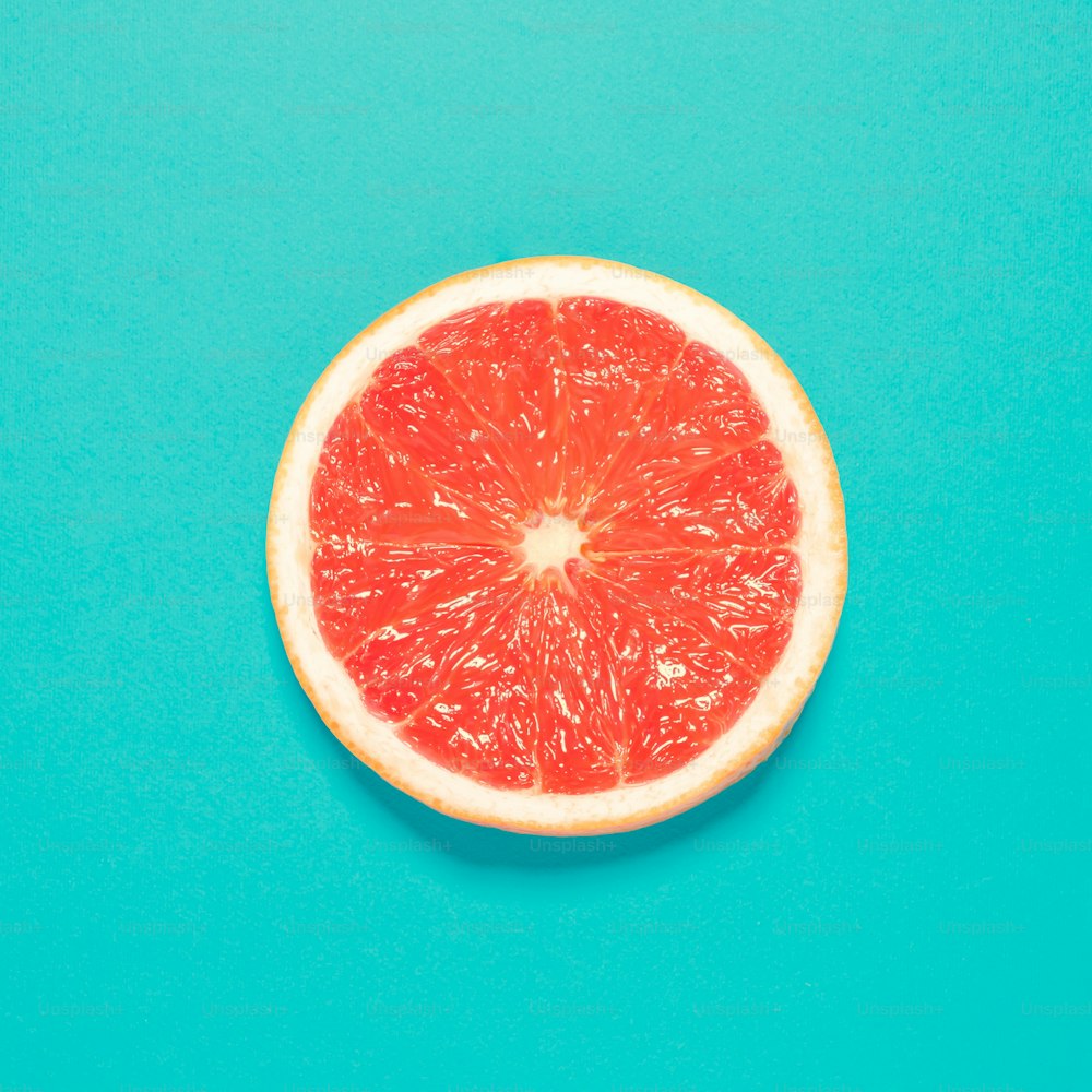 Grapefruit slice on pastel blue background. Minimal summer concept. Flat lay.