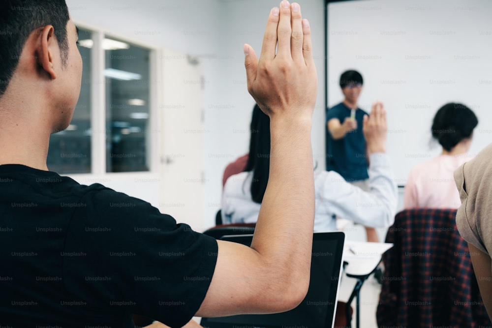 Students raising hands with teacher in college lecture room