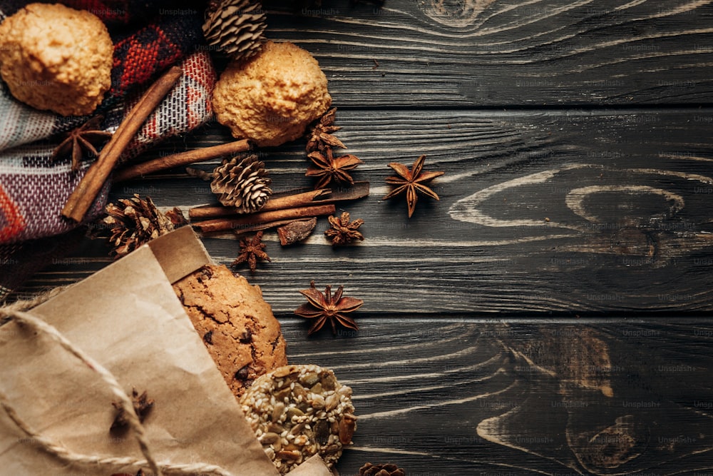 木製の背景にクッキー、カップケーキ、スパイス、スタイリッシュで素朴な冬のフラットレイ。テキスト用のスペース。居心地の良いムードの秋。季節の休日のベーカリーのコンセプト
