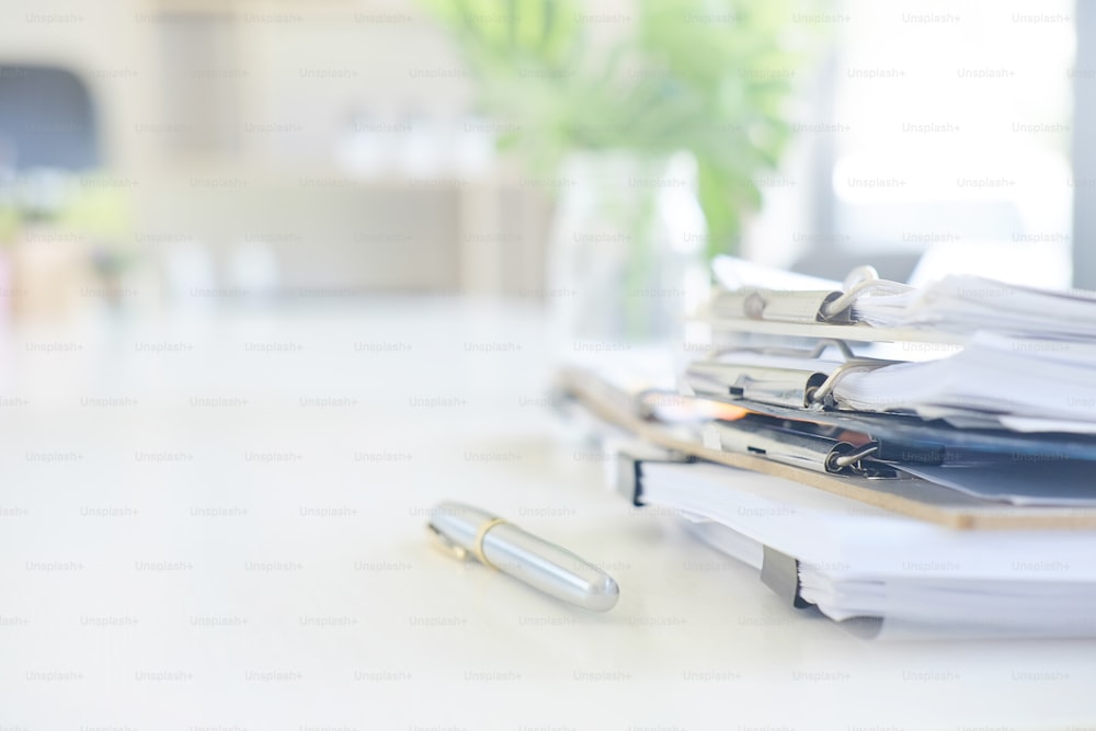 Stack of paper files and pen business equipment on office table.