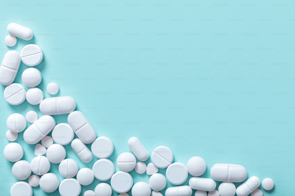 varie pillole bianche macro su sfondo blu, vista dall'alto