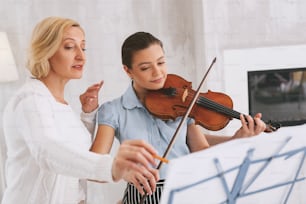 Repeat again. Attentive girl using her violin while remembering solfeggio