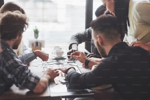 Group of creative friends sitting at wooden table. People having fun while playing board game.