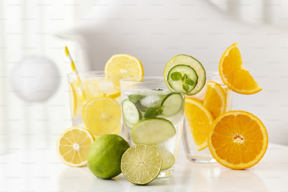 Bicchieri di acqua infusa con lime fresco, foglie di cetriolo e menta, limone e arancia. Messa a fuoco selettiva sulla metà del lime