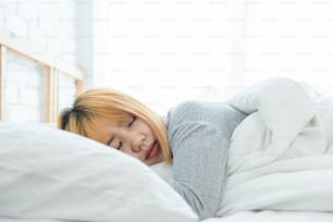 Beautiful young Asian woman sleeping in bed in the morning. Attractive asian girl use bedtime in her comfortable bedroom. Relaxation bedroom. Iifestyle asia woman at home concept.