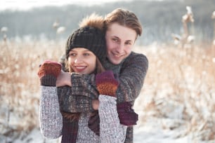 Happy young couple has fun on fresh snow at beautiful winter sunny day on vacation.