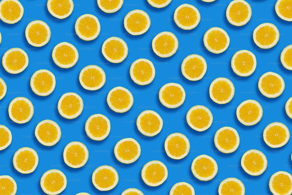 Zitronenmuster. Gelbe Zitronenscheiben auf blauem Papierhintergrund, trendiges flaches Lay. Sommerkonzept