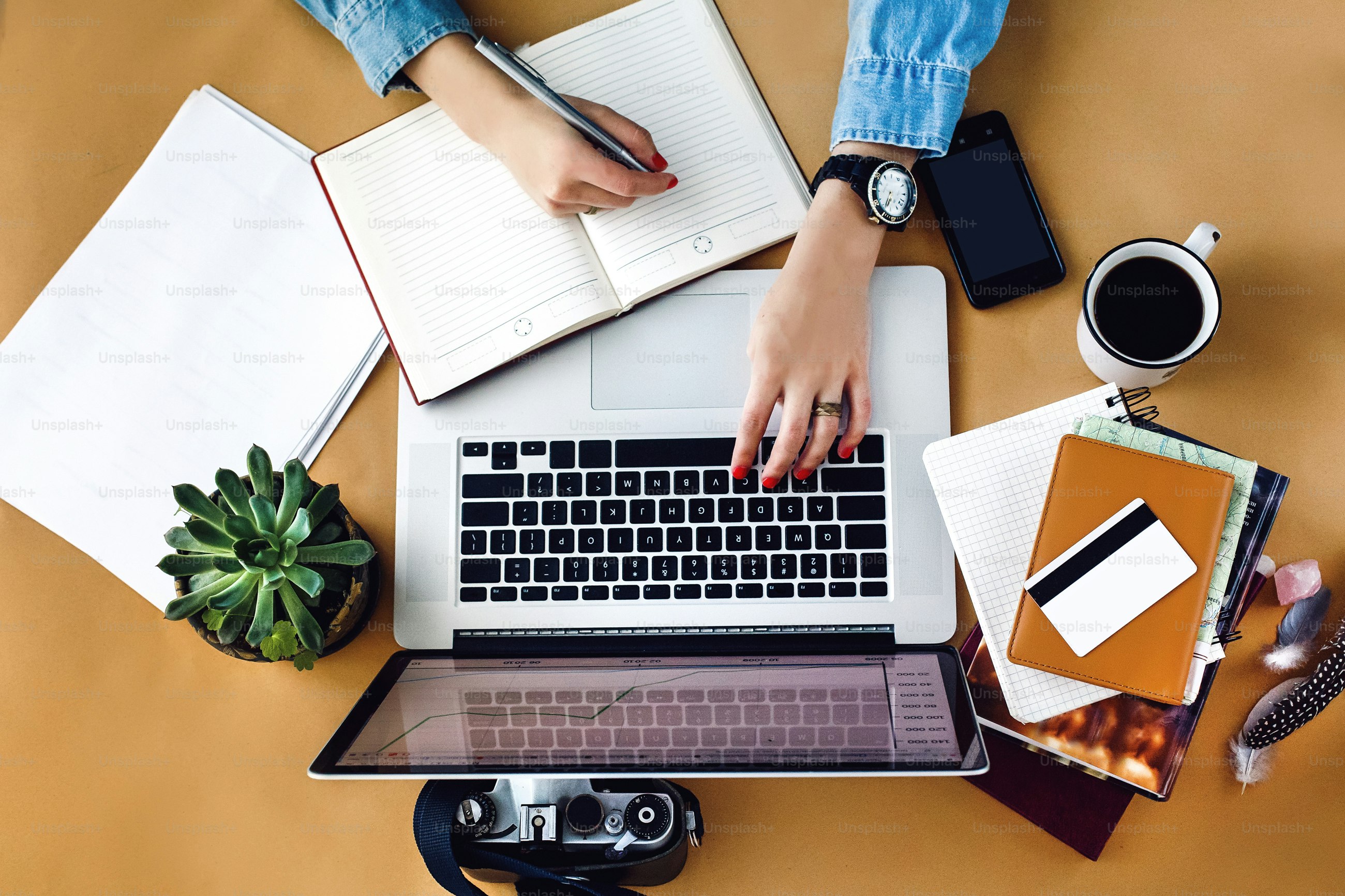 stylish young girl working  analytics holding pen on craft background with laptop and papers flat lay