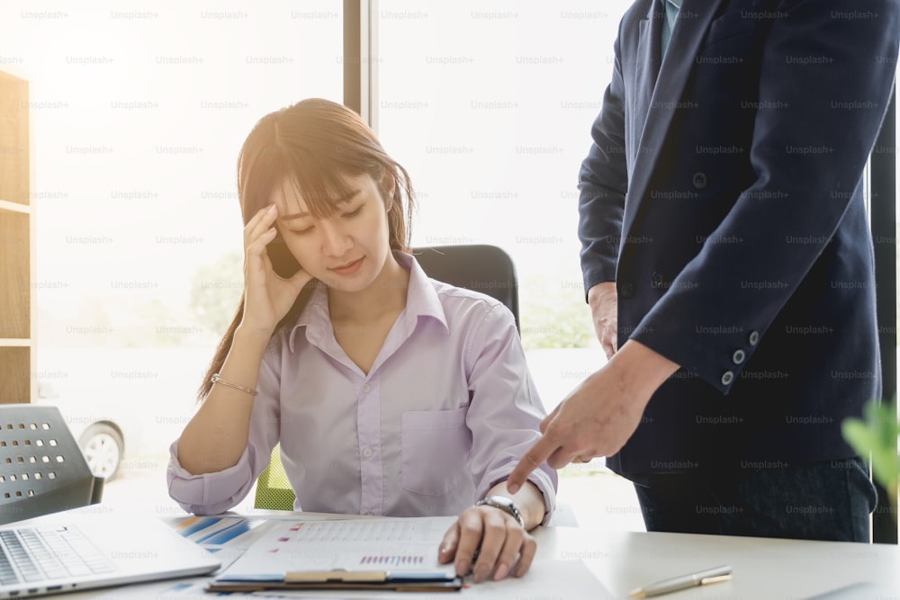 Serious boss looking at his employees while commenting a financial report document at meeting