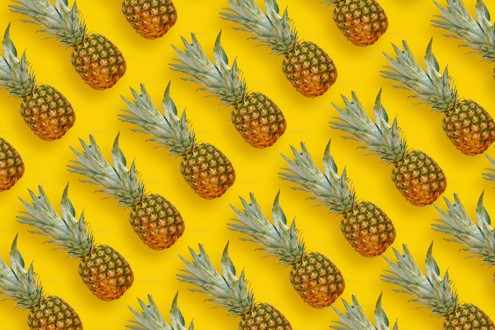 pineapple pattern. many pineapples on bright yellow paper background, trendy flat lay. summer concept