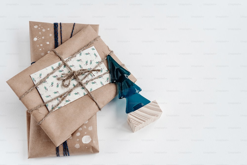 クラフト紙とクリスマスツリーの素朴なギフト、白い背景にシンプルな手作りのプレゼントとガラスのおもちゃ。季節のご挨拶。テキスト用のスペース