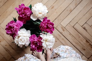beautiful bunch of peonies in vase on wooden background, rustic wallpaper concept, space for text