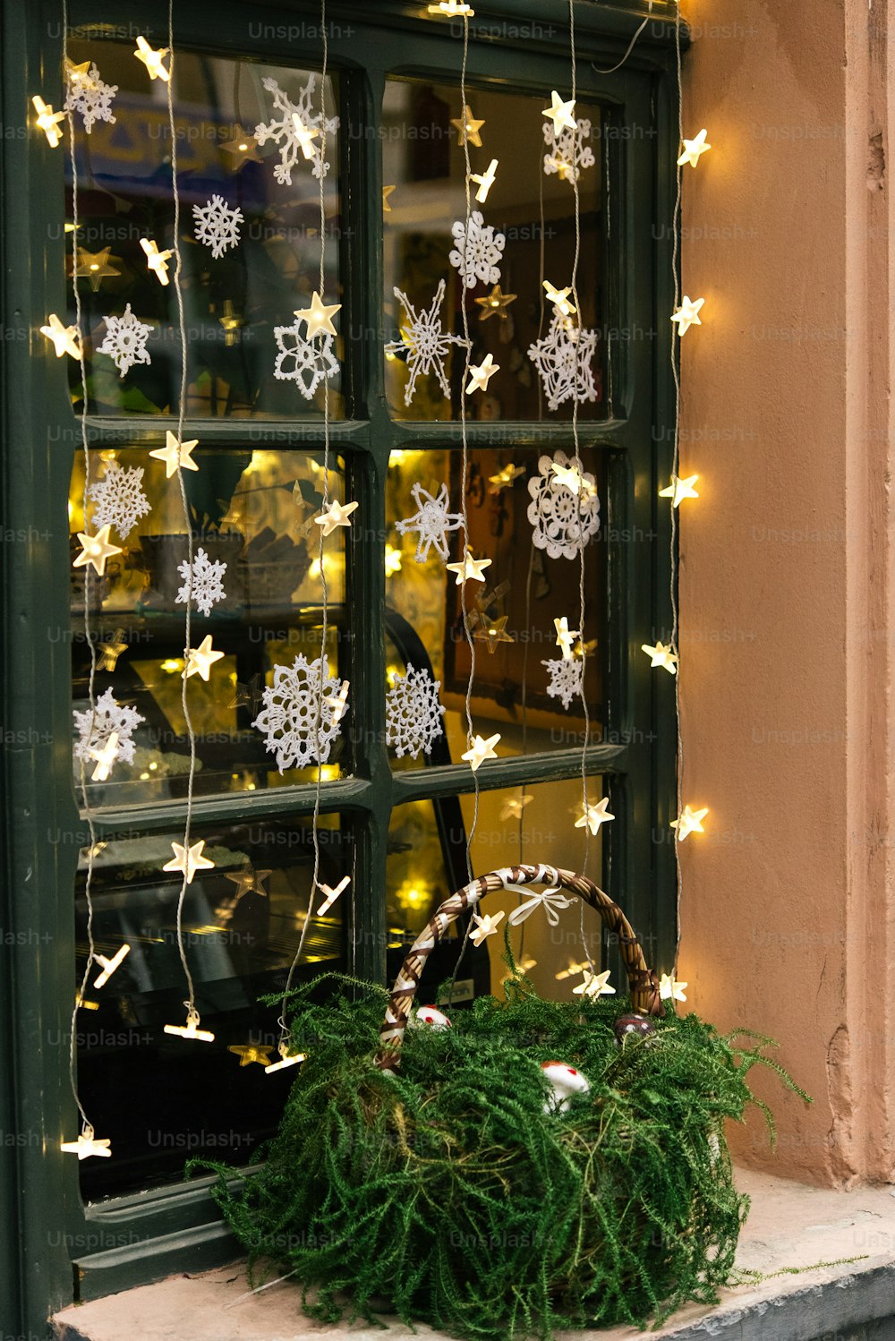 Stilvolle Luxus-Weihnachtsgirlande Lichter am Fenster und grüne Kiefer, Feierdekoration für Ferien in der Stadt