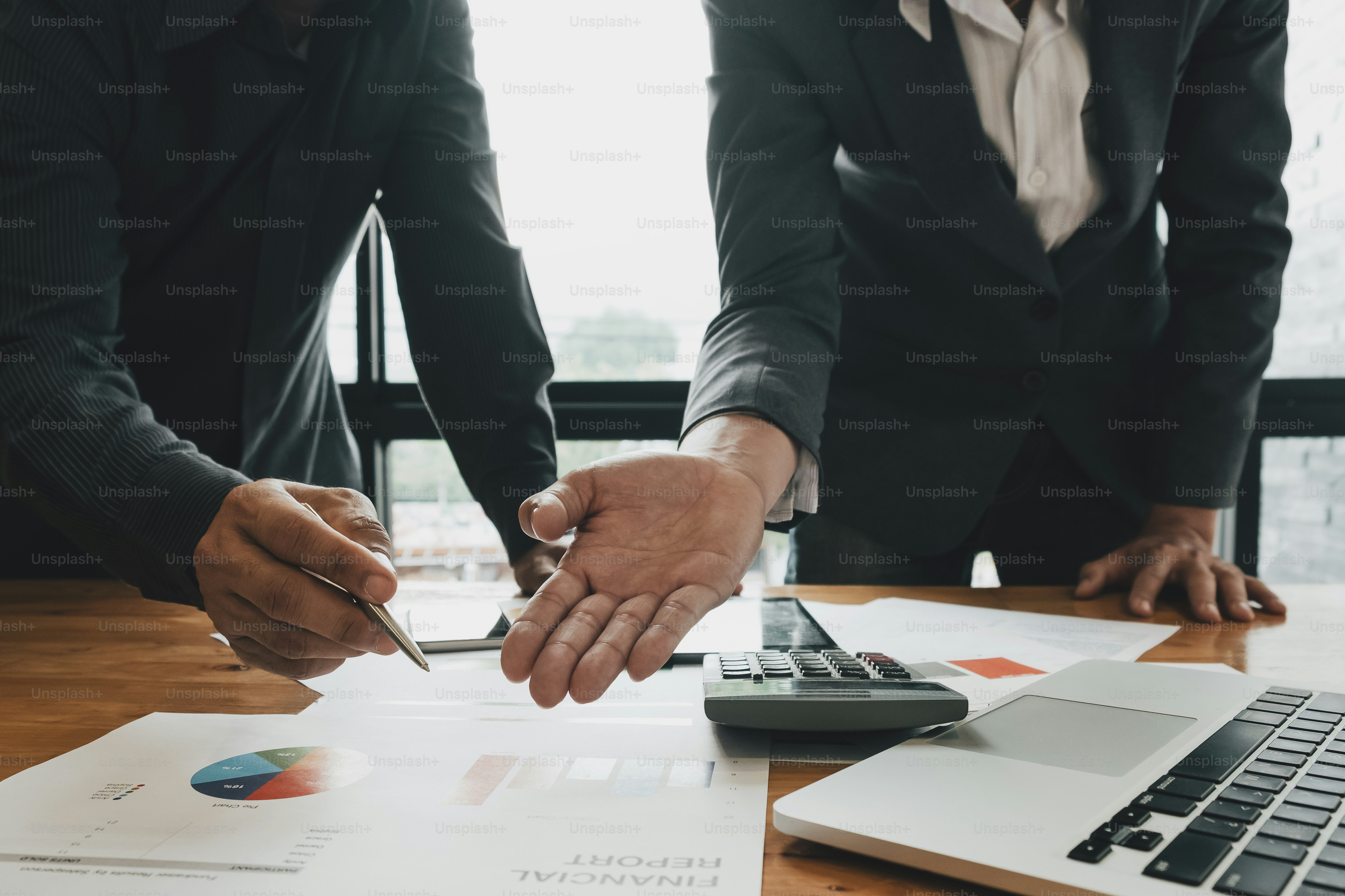 Joven empresario y socio señalando el informe financiero para analizar el plan de ventas de la empresa en la oficina.