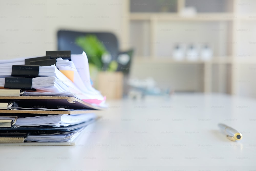 Pilha de arquivos de papel e caneta de equipamentos de negócios na mesa do escritório.