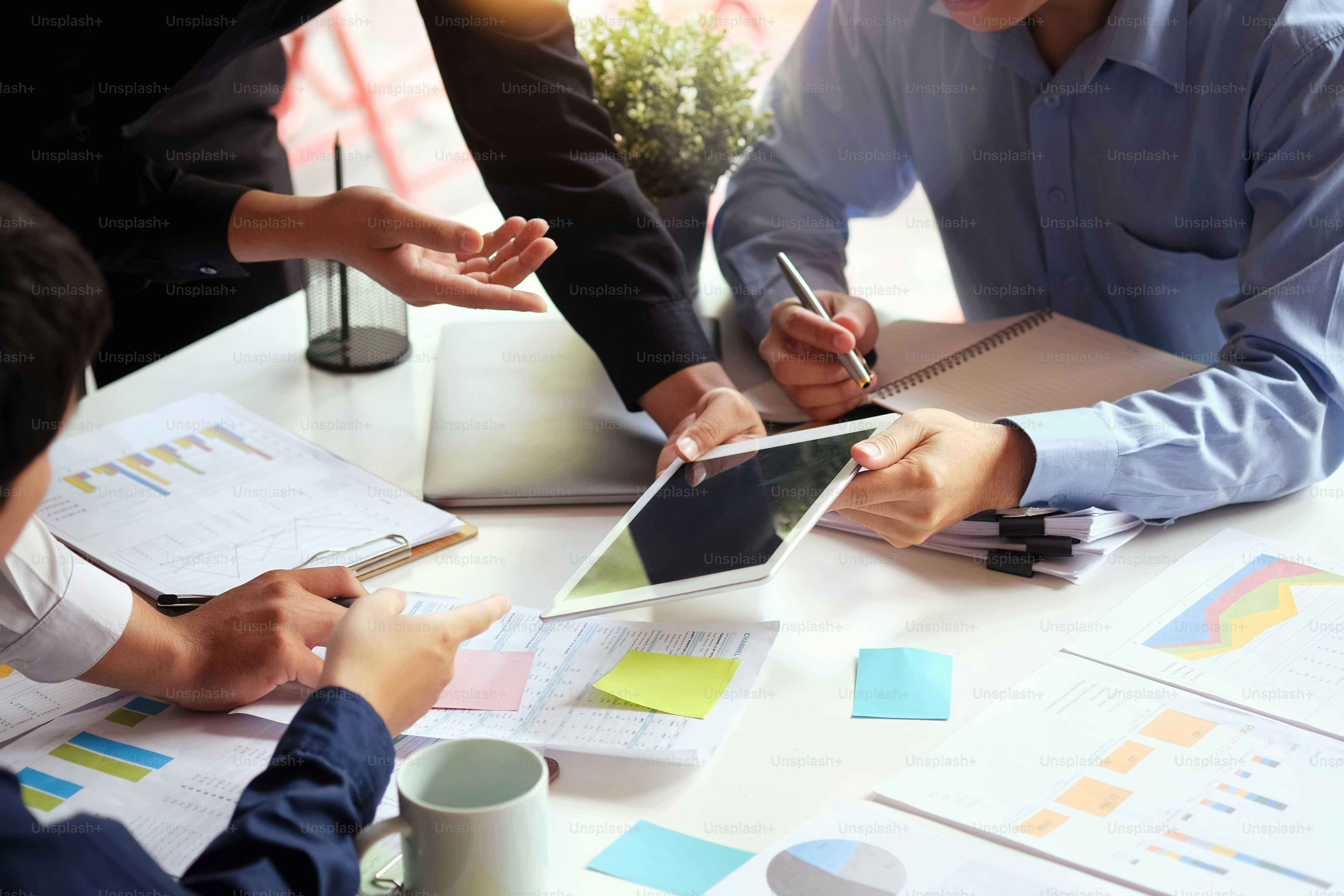 Cropped shot of a group of businesspeople discussing with tablet and paperwork in a meeting